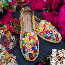 Load image into Gallery viewer, A pair of Nomad Espadrilles Beige footwear for women kept upon a cloth with colorful fabric in the background.