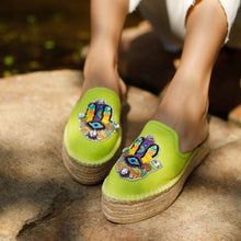 Load image into Gallery viewer, woman wearing a pair of Hamsa green espadrilles platform having evil eye protector design, sitting on a rock.