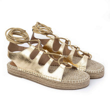 Load image into Gallery viewer, Photo of a pair of gold Gladiator Sandals featuring metallic gold straps on a white background.