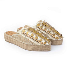 Load image into Gallery viewer, A pair of golden Espadrilles with a small detailing on them with a pattern around the bottom and sides on a white background.