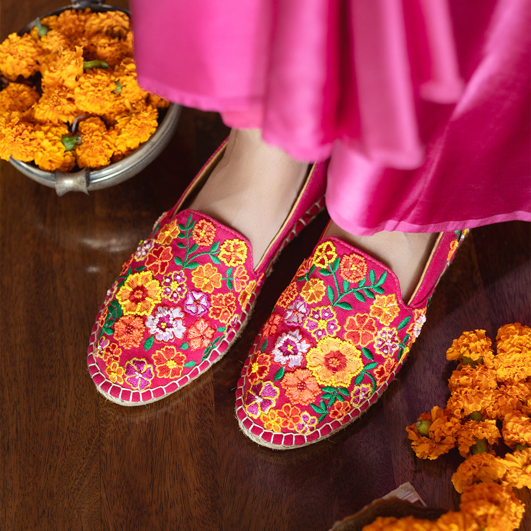 A woman has worn beautiful Bageecha Pink Espadrilles ladies shoes with some pooja flowers kept beside.