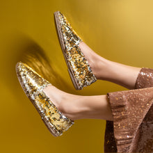 Load image into Gallery viewer, A Feet of lady wearing a Croshia flat Light Weight Sitara Espadrilles Gold, footwear for women kept against a yellow wall.

