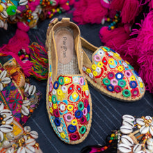Load image into Gallery viewer, A pair of Nomad Espadrilles Beige footwear for women kept upon a cloth with colorful fabric in the background.
