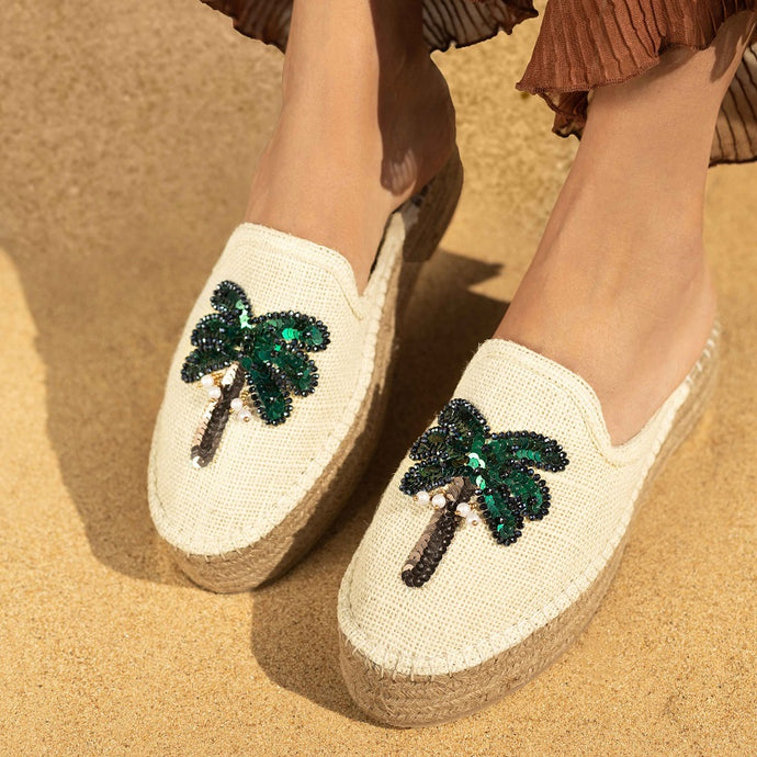woman wearing a pair of coco off-white espadrilles platform with a green palm tree on top of it