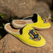 Load image into Gallery viewer, a pair of Hamsa green espadrilles flats having evil eye protector design, kept on a rock.
